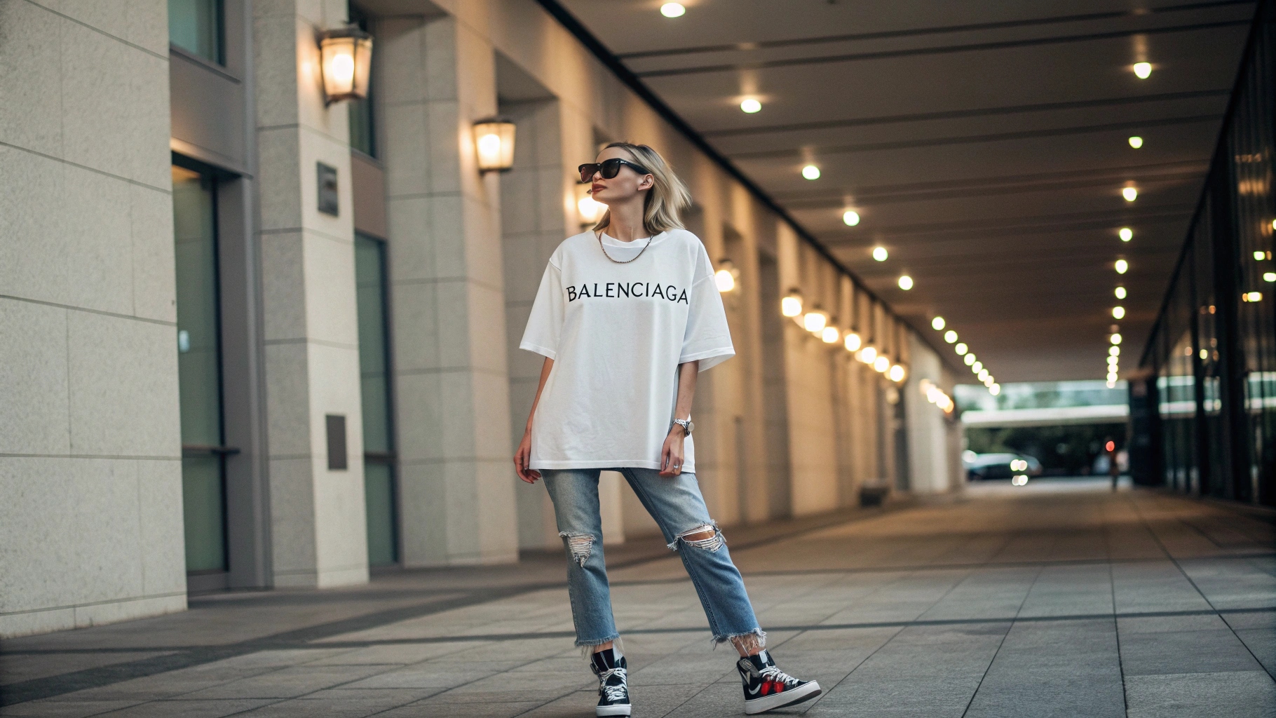 Fashion-forward model wearing an oversized Balenciaga T-shirt in streetwear style, paired with distressed jeans and high-end sneakers, creating a casual yet polished vibe. Set in a modern urban setting with an Instagram influencer aesthetic, soft lighting emphasizes the relaxed fit and comfort of the T-shirt, showcasing the subtle Balenciaga branding for an effortless cool street style look.